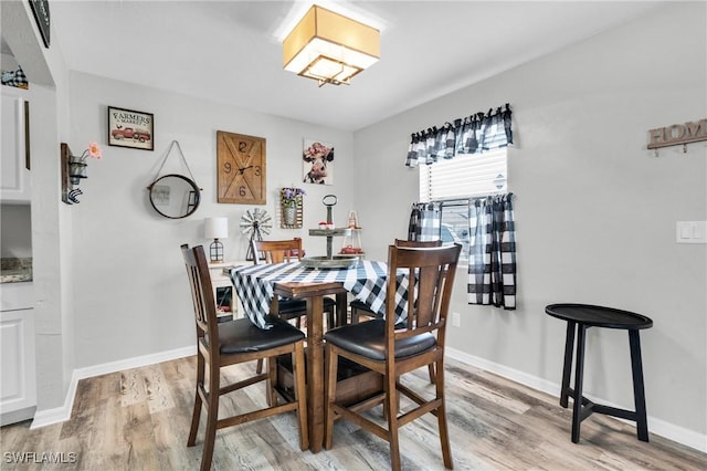 dining space featuring baseboards and light wood-type flooring