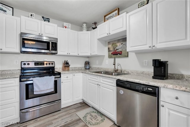 kitchen featuring light wood-style flooring, appliances with stainless steel finishes, white cabinetry, and a sink