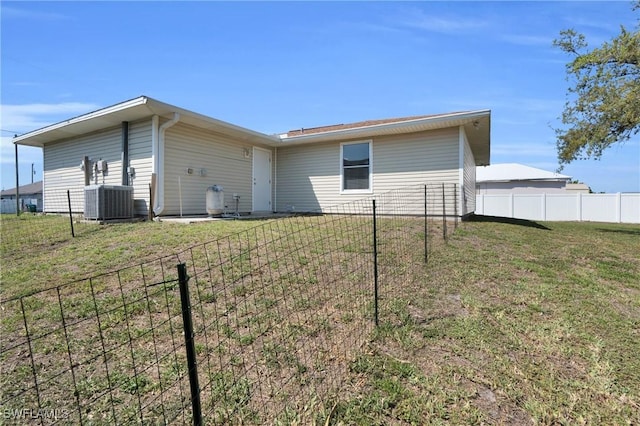 back of house with cooling unit, a lawn, and fence