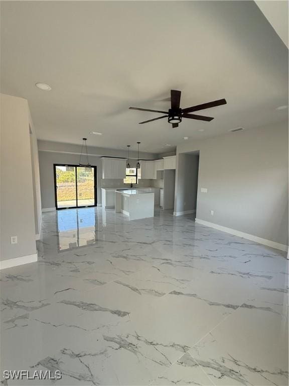 unfurnished living room featuring marble finish floor, a ceiling fan, and baseboards