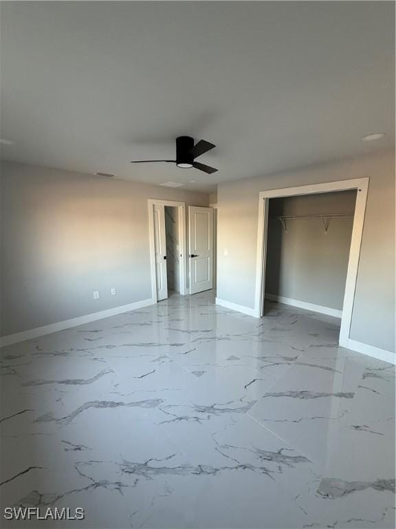 unfurnished bedroom with a closet, baseboards, marble finish floor, and ceiling fan