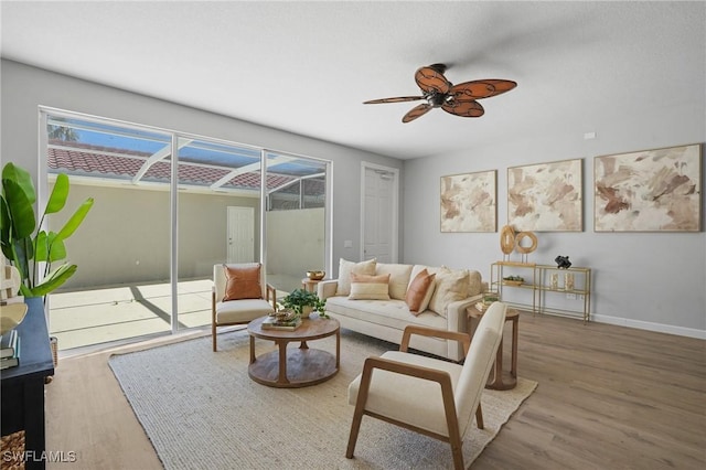 living room featuring wood finished floors, baseboards, and ceiling fan