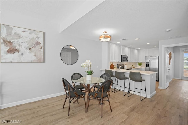 dining area with recessed lighting, light wood-style flooring, and baseboards