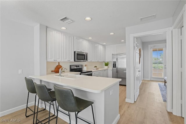 kitchen with a kitchen bar, light wood-style flooring, visible vents, and stainless steel appliances