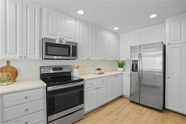 kitchen with stainless steel appliances, light wood-style floors, white cabinets, and light countertops