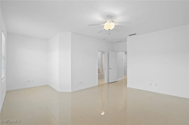 spare room featuring light tile patterned floors, visible vents, baseboards, and a ceiling fan