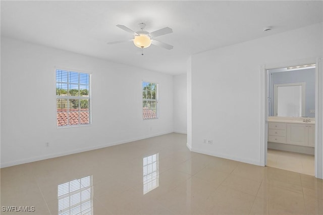 empty room featuring light tile patterned floors, ceiling fan, and baseboards