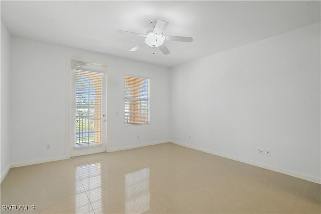 spare room featuring light tile patterned floors, a ceiling fan, and baseboards