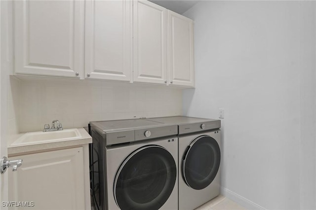 laundry area featuring baseboards, cabinet space, independent washer and dryer, and a sink