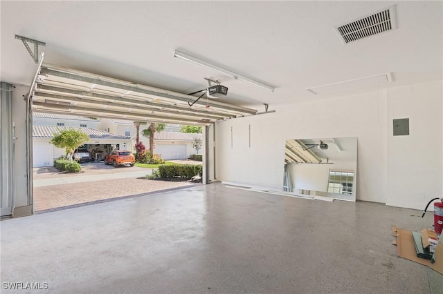 garage featuring electric panel, visible vents, and a garage door opener