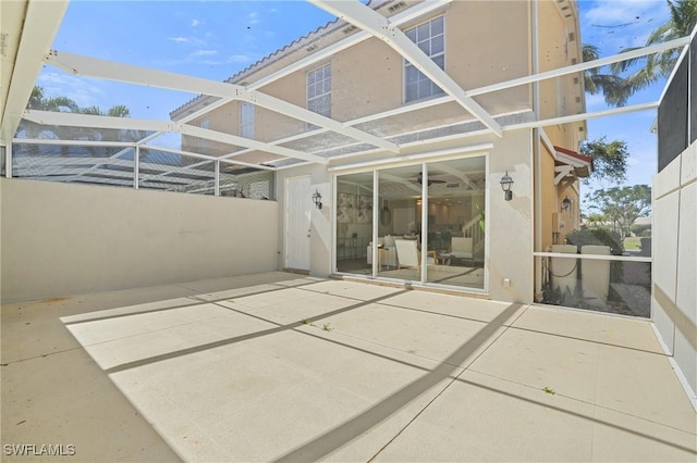 back of house featuring glass enclosure, a patio, and stucco siding