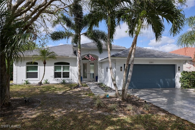 ranch-style home with driveway, stucco siding, french doors, a garage, and a tiled roof