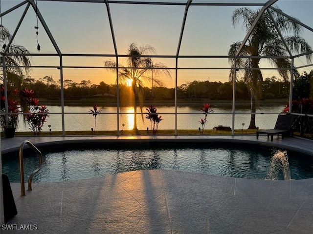 pool at dusk with an outdoor pool, glass enclosure, a patio, and a water view