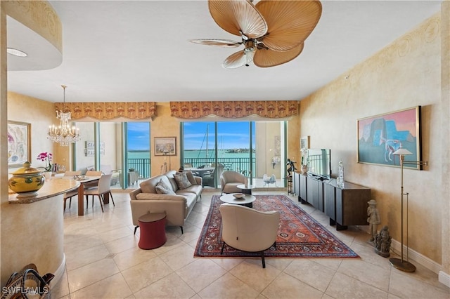 living room featuring light tile patterned flooring, ceiling fan with notable chandelier, and baseboards