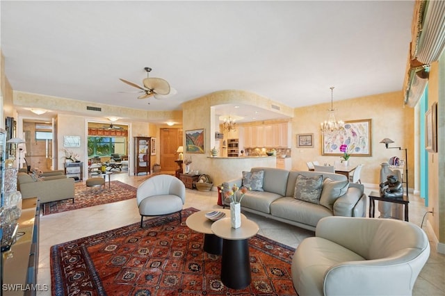 tiled living room featuring visible vents, ceiling fan with notable chandelier, and baseboards