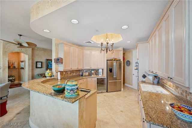 kitchen featuring visible vents, high end fridge, wine cooler, a peninsula, and light stone countertops