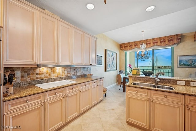 kitchen featuring white stovetop, a sink, light stone counters, backsplash, and light tile patterned floors