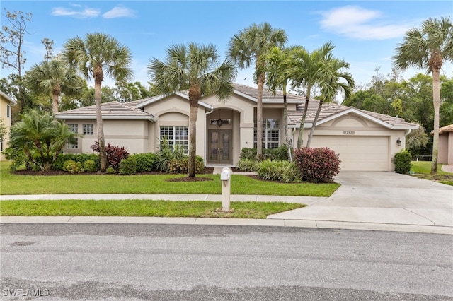 12922 Kedleston Cir, Fort Myers, FL 33912 - view of front of house with french doors, stucco siding, an attached garage, driveway, and a front yard