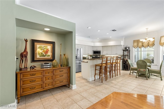 12922 Kedleston Cir, Fort Myers, FL 33912 - kitchen featuring stainless steel appliances, a chandelier, light tile patterned floors, a breakfast bar, and crown molding