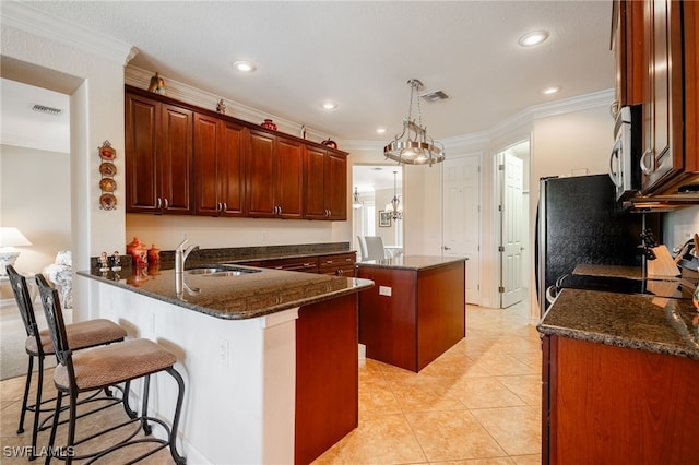 kitchen featuring visible vents, stainless steel microwave, a center island, a peninsula, and a sink