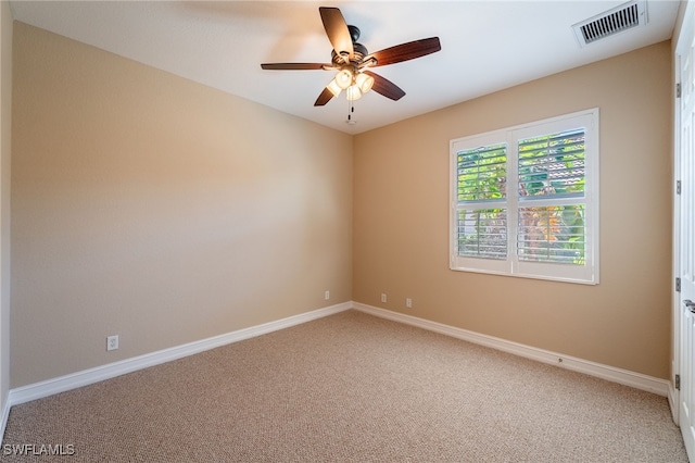 spare room featuring light carpet, visible vents, a ceiling fan, and baseboards