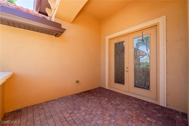 entrance to property with stucco siding, french doors, and a patio