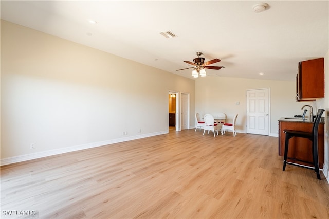 interior space with visible vents, ceiling fan, baseboards, light wood-style floors, and a sink