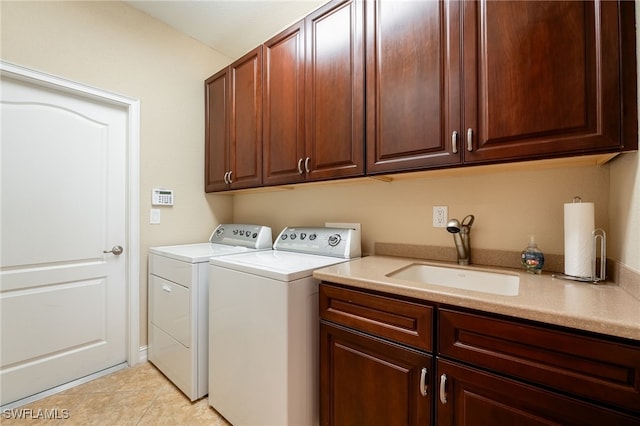 washroom featuring a sink, cabinet space, washing machine and dryer, and light tile patterned flooring