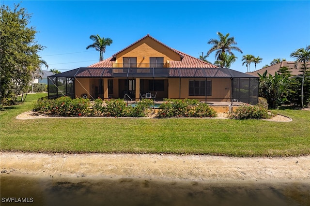 view of front of property with stucco siding, a tile roof, a front yard, a balcony, and a lanai