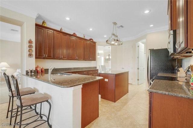 5220 SW 22nd Ave, Cape Coral, FL 33914 - kitchen with white microwave, a center island, ornamental molding, dark stone counters, and a peninsula