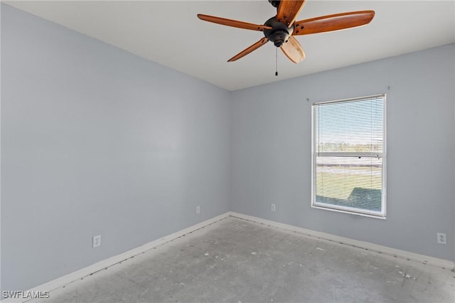 spare room with baseboards, concrete floors, and a ceiling fan