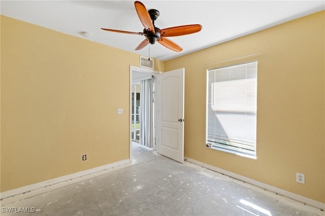 unfurnished room with unfinished concrete floors, a ceiling fan, visible vents, and baseboards