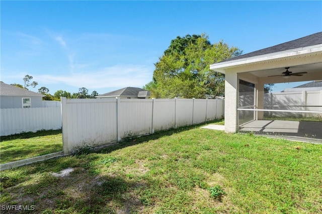 view of yard featuring a sunroom, a ceiling fan, and a fenced backyard