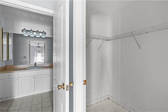 walk in closet featuring a sink, light floors, and ceiling fan