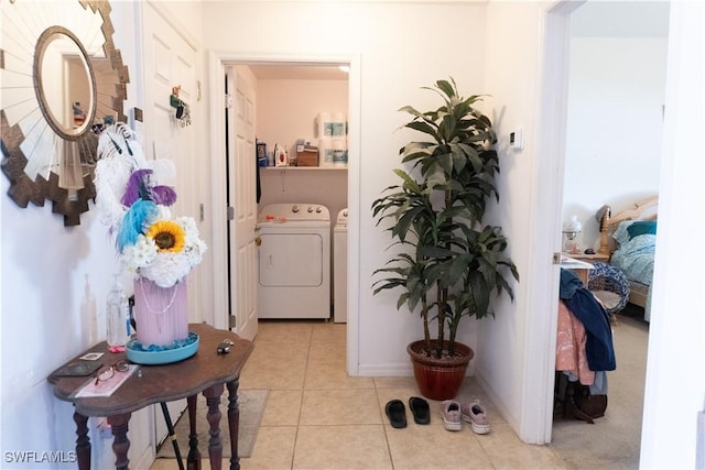 hallway with light tile patterned flooring, baseboards, and washing machine and clothes dryer