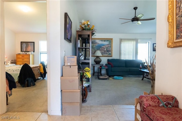 carpeted living area with tile patterned floors and ceiling fan