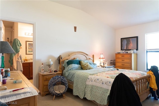 bedroom with lofted ceiling, light carpet, and ensuite bath