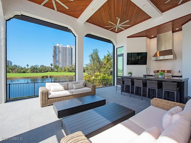 view of patio with exterior kitchen, a sink, ceiling fan, a water view, and outdoor lounge area