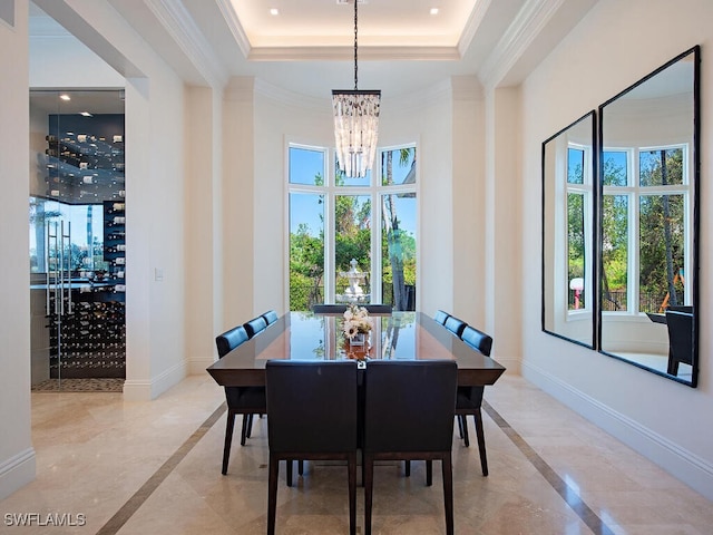 dining room with a tray ceiling, baseboards, and ornamental molding