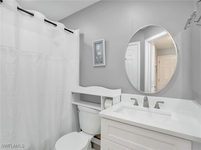 bathroom featuring a shower with shower curtain, toilet, and vanity