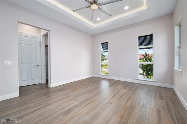 empty room featuring baseboards, a raised ceiling, and wood finished floors