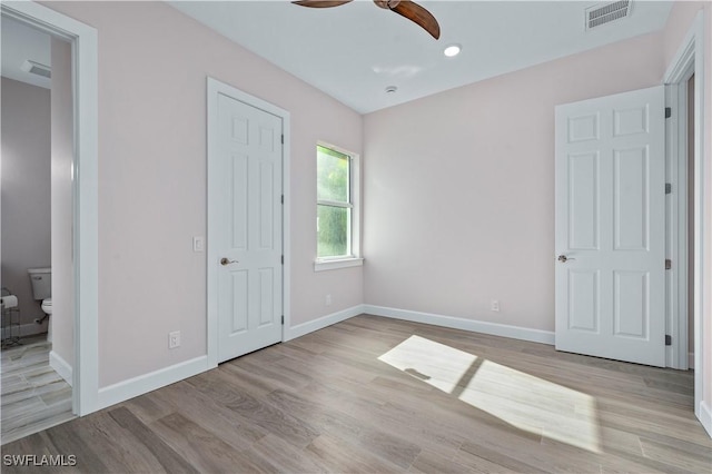 unfurnished bedroom featuring a ceiling fan, light wood-style floors, baseboards, and visible vents