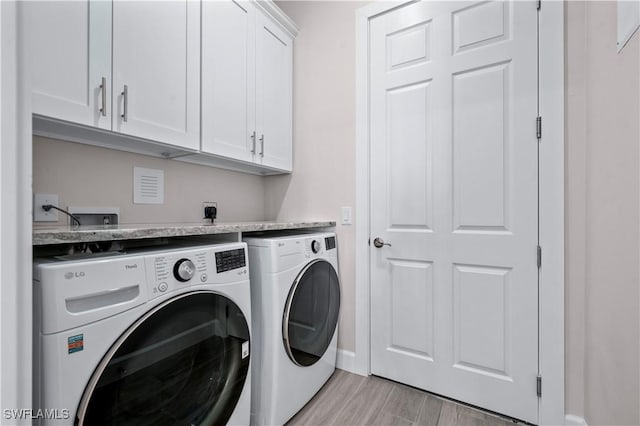 laundry room featuring washer and dryer, baseboards, cabinet space, and light wood-style flooring