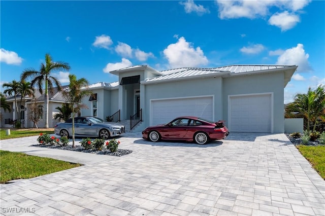 view of front of house featuring stucco siding, a standing seam roof, decorative driveway, an attached garage, and metal roof