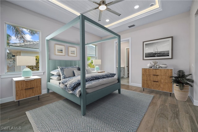 bedroom featuring wood finished floors, visible vents, baseboards, a tray ceiling, and recessed lighting