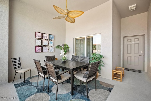 dining room featuring visible vents, ceiling fan, a towering ceiling, and a textured wall