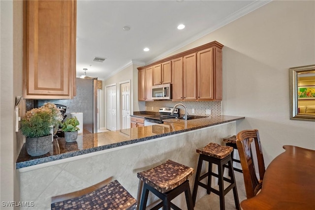 kitchen featuring dark stone countertops, decorative backsplash, vaulted ceiling, appliances with stainless steel finishes, and crown molding