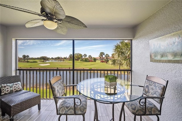 sunroom with a water view and ceiling fan