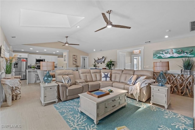 living room with lofted ceiling with skylight, light wood-style flooring, a ceiling fan, and visible vents