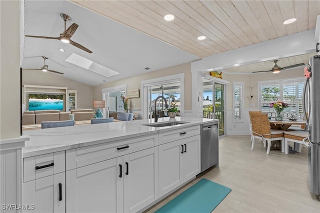 kitchen with a sink, stainless steel appliances, ceiling fan, and white cabinets